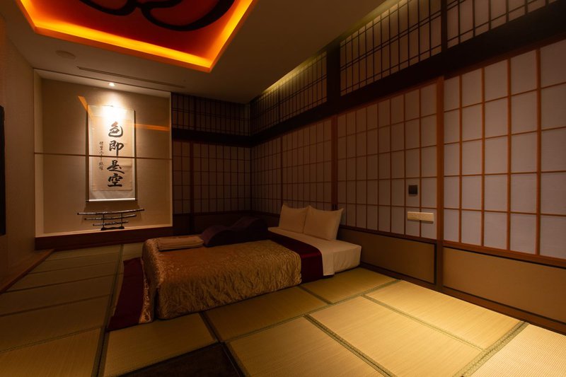日式風格的榻榻米房型，懸掛「色即是空」的書法搭配昏暗燈光。